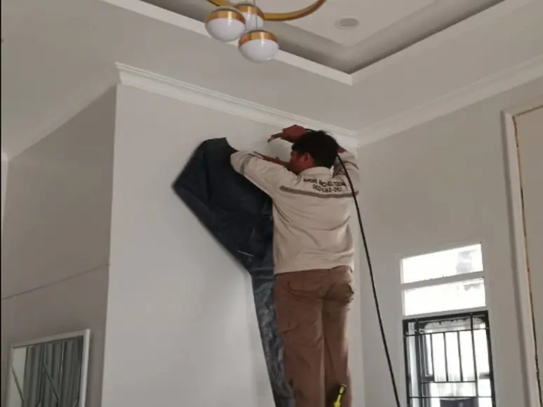 Teknisi membersihkan unit indoor AC yang ditutup terpal pelindung
