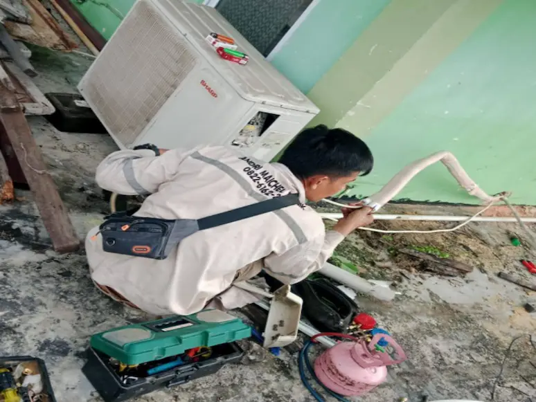 Teknisi memeriksa sambungan pipa pada unit outdoor AC
